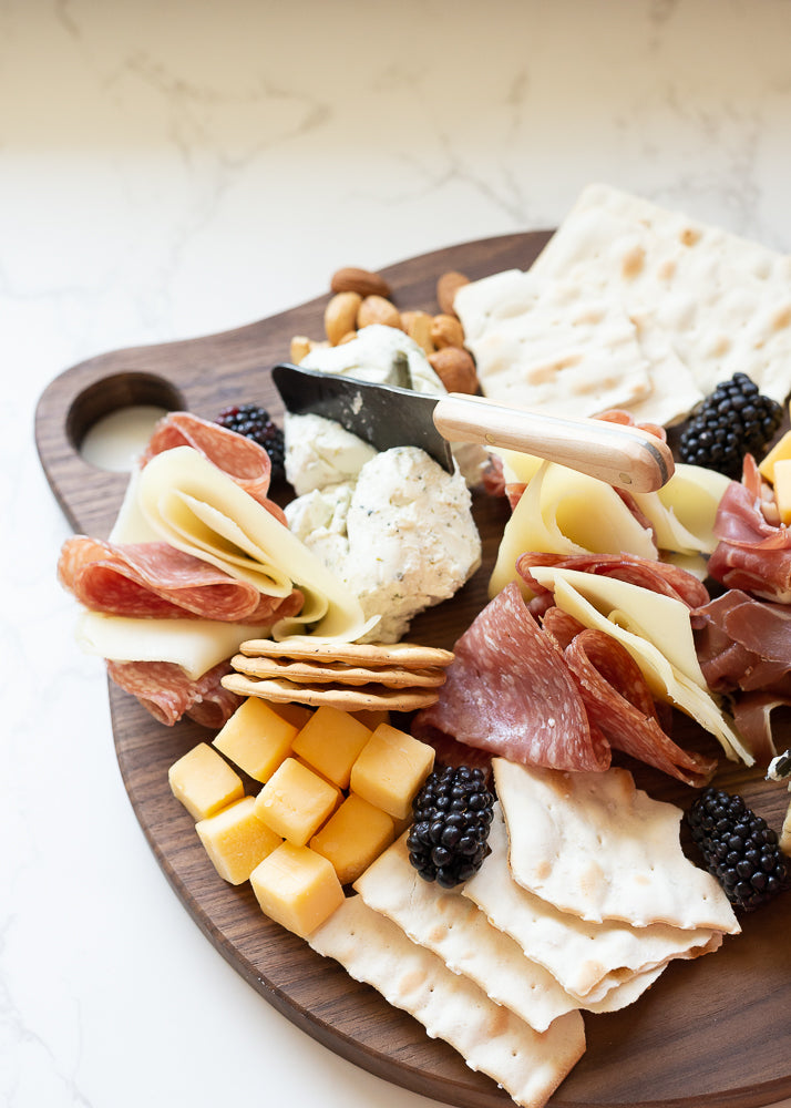 Handcrafted Round Cutting Board with Assorted Cheeses and Crackers Displayed on It