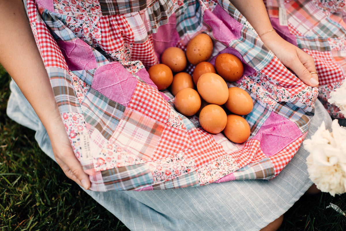 The Child's Quilted Patchwork Apron Holding Eggs