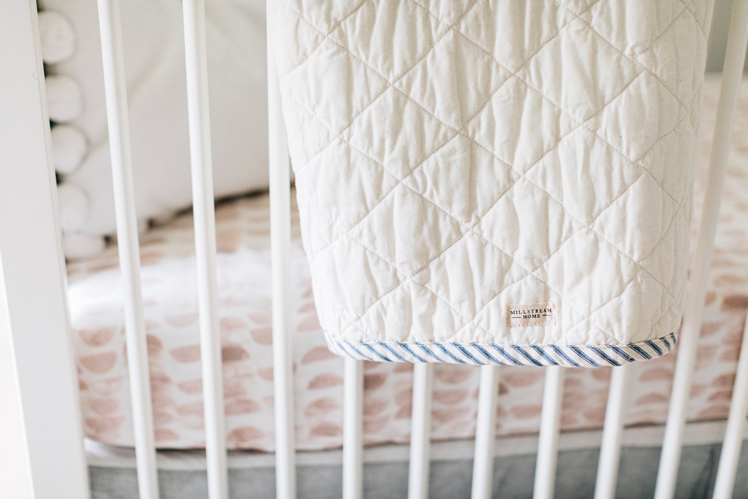 The Child's Quilted Blanket Up Close Hanging on a Crib