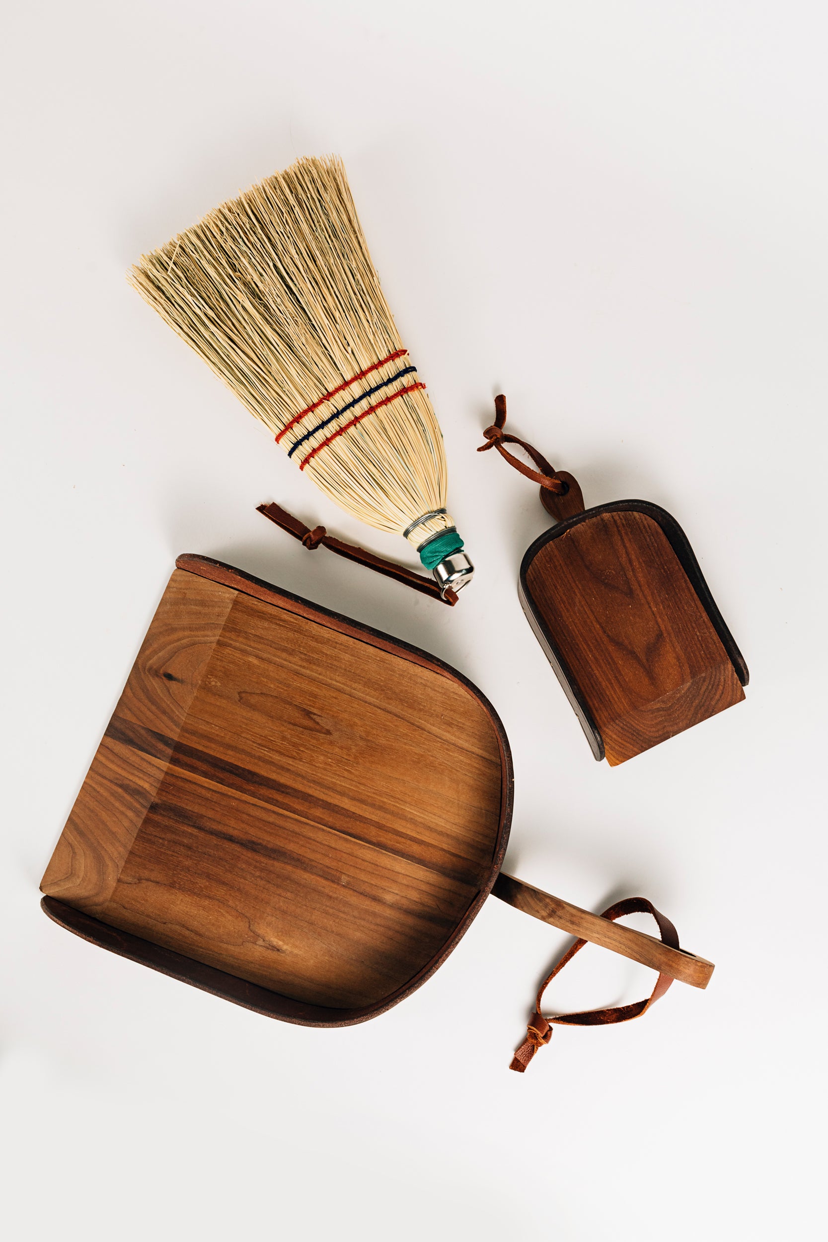 The Child's Leather and Wood Dustpan Next to a Hand Broom and Dustpan