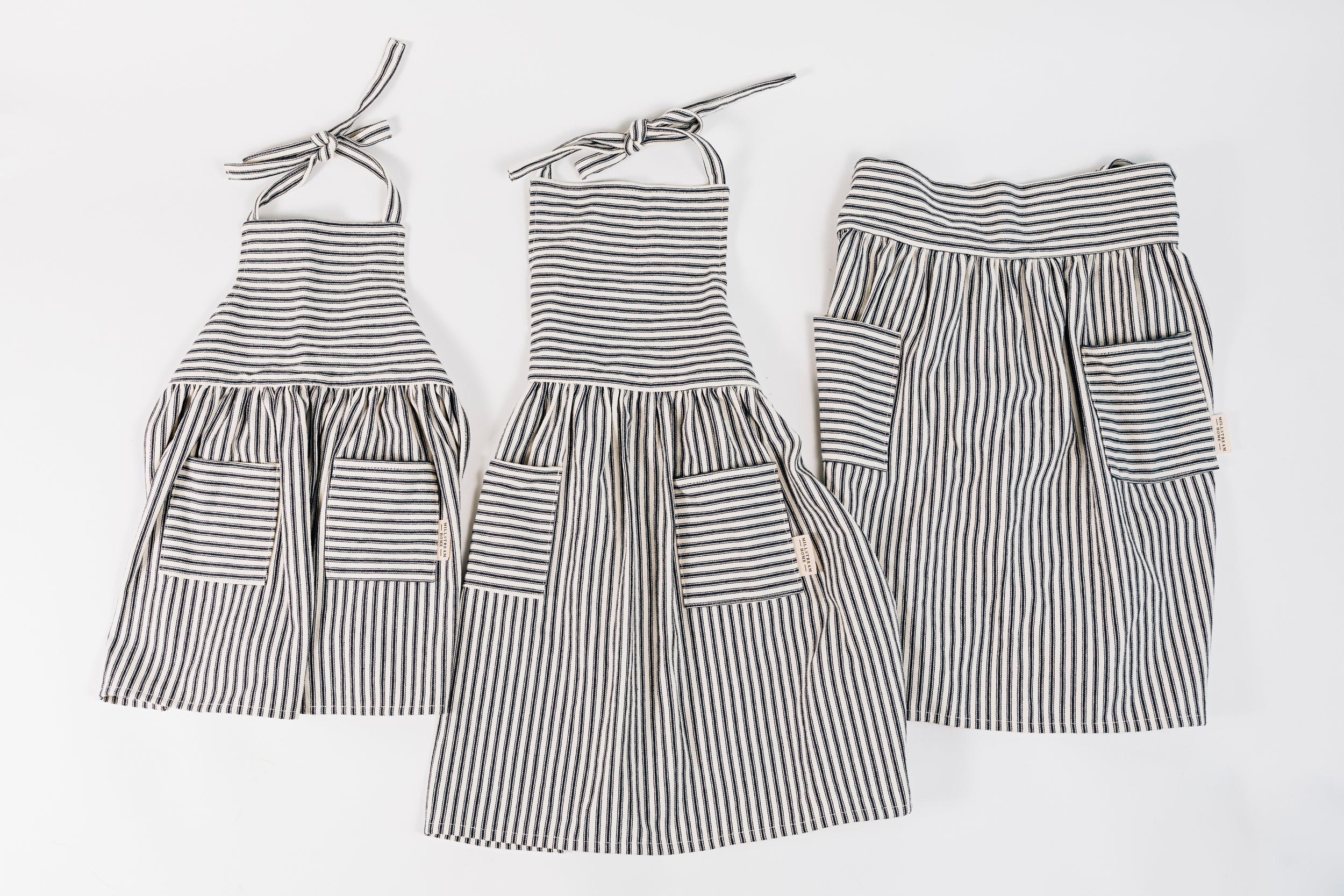 The Child's Ticking Apron Next to Two Adult Aprons